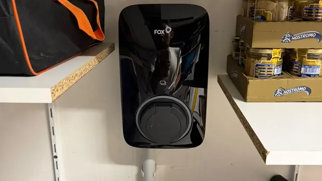 Borne de recharge murale noire Fox ESS avec sa prise de charge, fixée entre deux étagères