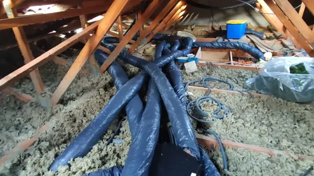 Gaines de ventilation isolées noires réparties entre les fermettes, posées sur l'isolant en vrac des combles