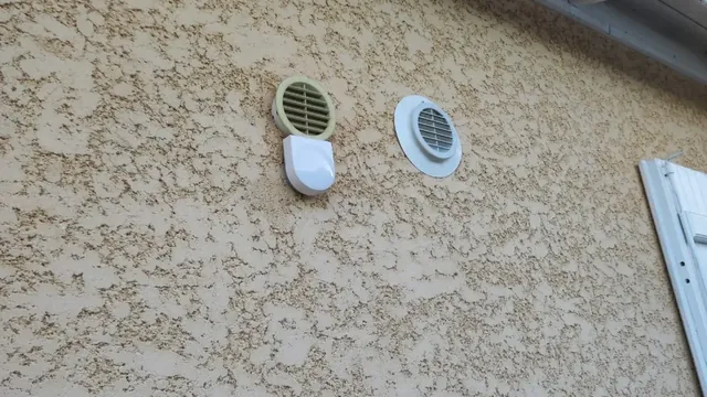 Deux grilles d'aération rondes et un capot blanc fixés sur une façade crépie