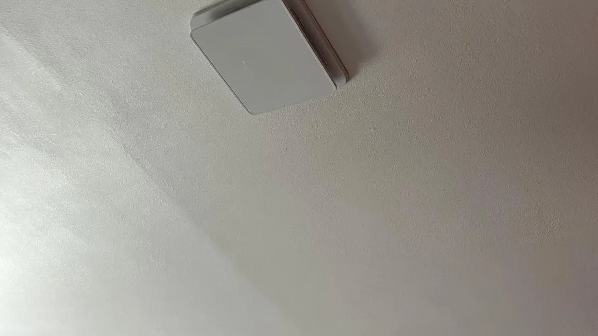 Bouche d'extraction carrée blanche fixée au plafond d'une pièce